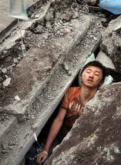 Un joven espera a ser rescatado de entre las ruinas de un edificio en Beichuan