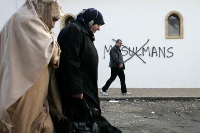 Musulmanes junto a una pintada racista en Saint-Etienne.