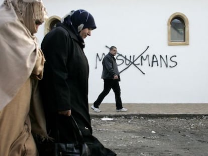 Musulmanes junto a una pintada racista en Saint-Etienne.