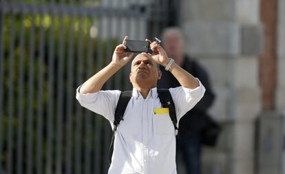 Un ciudadano graba con su móvil a los activistas de Greenpeace durante su escalada por una de las Torres Kio de Madrid.
