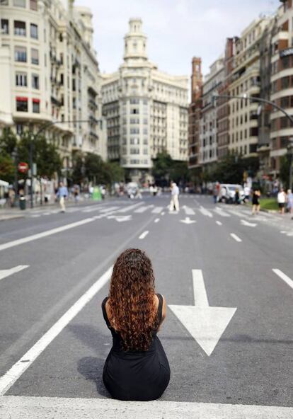 Una joven aprovecha para sentarse en la calzada frente a la plaza del Ayuntamiento de Valencia con motivo del Día Sin Coches.