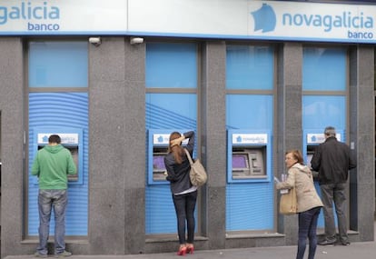 Varios usuarios de los cajeros en una sucursal de Novagalicia Banco, en Santiago de Compostela.
