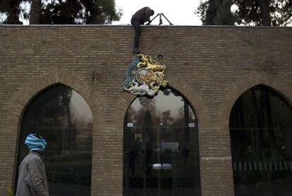 Un manifestante retira el escudo británico de la fachada de la Embajada en Teherán, tras el asalto a la legación diplomático.