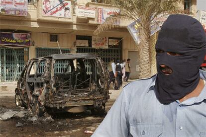 Un policía iraquí, junto al coche bomba que ha estallado en un barrio chií de Bagdad.