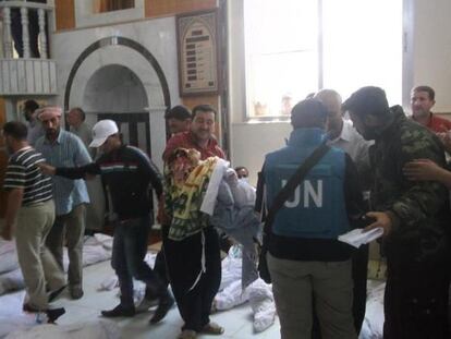 Observadores de la ONU hablan con habitantes de Hula en la morgue donde se acumulan los cadáveres de los bombardeos del viernes en la ciudad.