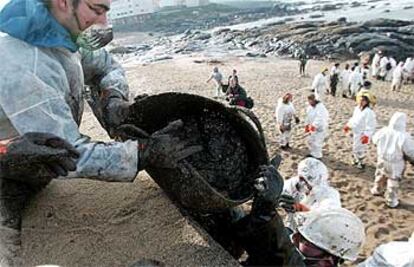 Un grupo de voluntarios trabajaba ayer en la recogida del fuel que ennegrece la playa de la localidad coruñesa de Muxía.