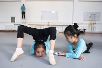 Una niña pone en marcha el cronómetro para que su compañera sepa cuánto tiempo tiene que mantenerse doblada de esa forma. Los entrenamientos son extenuantes. Y peligrosos. Los niños más pequeños se contorsionan hasta poner en entredicho los límites del cuerpo humano. Lo que más trabajan es la flexibilidad, porque es lo que se pierde con mayor facilidad.