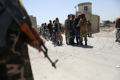 Guerrilleros talibanes cachean a los trabajadores que abandonan el aeropuerto de Kabul, este domingo.