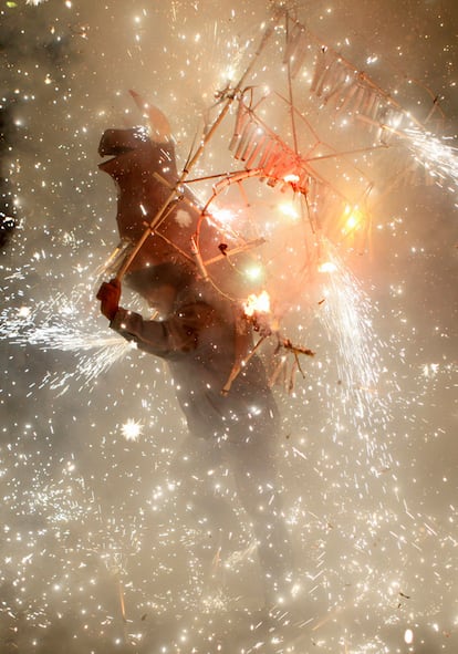 Un hombre porta un 'torito', hecho de papel, mientras los juegos artificiales explotan durante la celebración de del día de San Santiago.