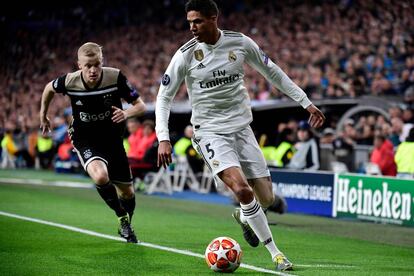 El defensa del Real Madrid, Raphael Varane, protege el balón ante la presión del jugador del Ajax, Donny van De Beek.