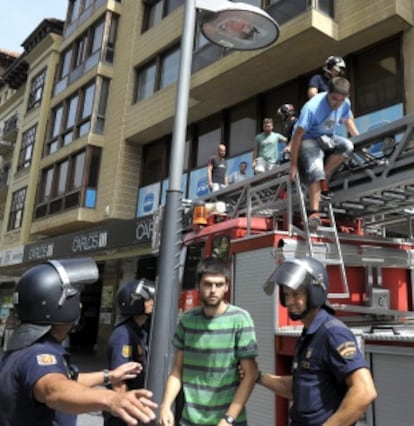 Los bomberos ayudan a descender de la fachada de la sede del PP en Pamplona a los seis detenidos por desórdenes públicos.