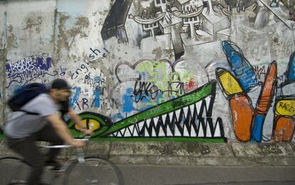 Un ciclista ante uno de los murales de la East Side Gallery, en Berlín.