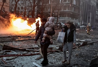 Una familia camina entre los escombros de un edificio dañado en un ataque con misiles en Kiev, este viernes.