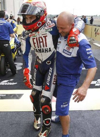 Un mecánico ayuda a Lorenzo a caminar tras la carrera.