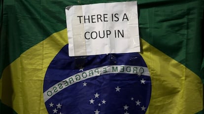 "Há um golpe", diz o cartaz em inglês, diante da bandeira do Brasil, carregado por um manifestante em São Paulo. 