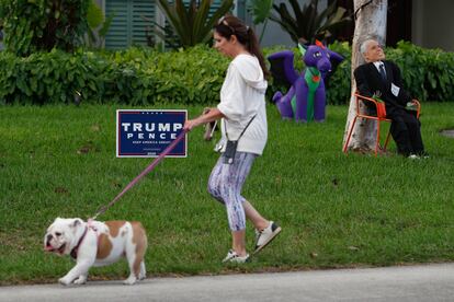 Una mujer pasea a su perro en una calle de Miami, este sábado 31 de octubre.