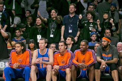 Un grupo de aficionados de los Nets animan a su equipo detrás del banquillo de los Knicks.