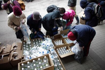 Varios ciudadanos recogen botellas de agua mineral en un centro de distribución de alimentos en Yamada, al norte de Japón.