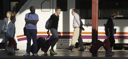 Varios pasajeros de tren con equipajes caminan por un andén de la estación de Chamartín.