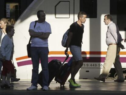 Varios pasajeros de tren con equipajes caminan por un and&eacute;n de la estaci&oacute;n de Chamart&iacute;n. 