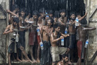 Varios migrantes, que fueron encontrados en un barco en el mar, recogen agua de lluvia en un campamento de refugio temporal cerca del embarcadero de Kanyin Chaung, en Myanmar.