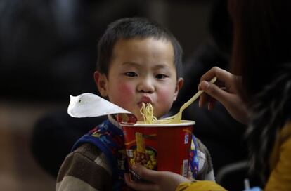 Una madre alimenta a su hijo con fideos instantáneos mientras espera un tren en la estación de Zhengzhou, provincia de Henan (China), 19 de febrero de 2014.