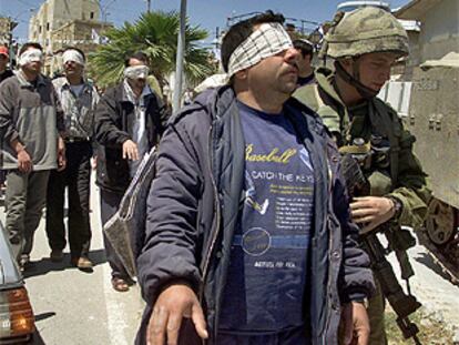Miembros del ejército israelí conduce a uno de los palestinos detenidos durante la incursión en Hebrón.