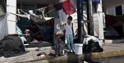 Una niña afgana ayuda a su hermana a lavarse delante de su tienda en los alrededores del antiguo aeropuerto internacional de Atenas (Grecia).