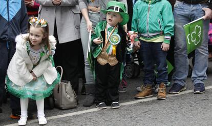 Unos niños esperan entre el público a que pasen los participantes en el desfile de Belfast, Irlanda del Norte.