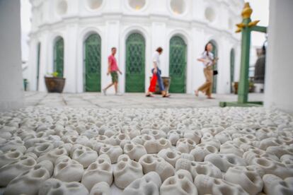 Varios visitantes pasan junto a la obra 'Lo que dejarás atrás', del artista tailandés Nino Sarabutra, dentro del templo Wat Prayoot en la sala donde se guardan cenizas, durante la celebración de la Bienal de arte de Bangkok (Tailandia).