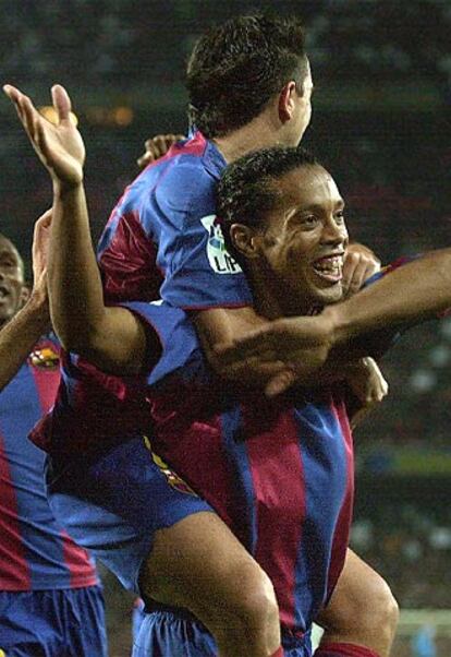 Ronaldinho es abrazado por Xavi tras marcar el tercer gol, de penalti, un resultado que sita a su equipo con siete puntos de diferencia sobre el Madrid y deja bien claro que el mejor equipo del campeonato liguero es el azulgrana.