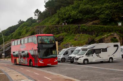 El autobús turístico de San Sebastián circula junto a unas autocaravanas aparcadas en el paseo Nuevo de la ciudad.