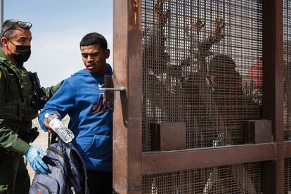 A Border Patrol agent searches a group of migrants who were let through concertina wire by Texas National Guard