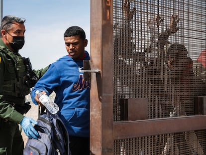 A Border Patrol agent searches a group of migrants who were let through concertina wire by Texas National Guard