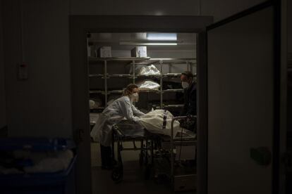 Marina Gómez y Manel Rivera, dos trabajadores funerarios, depositan el cuerpo de una víctima de la covid en la morgue de su empresa. Mémora, en Barcelona.