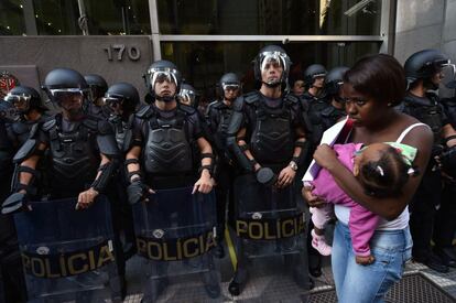 Uma mulher com a filha passa em frente a um bloqueio policial durante o quinto dia de greve dos metroviários em São Paulo, que coincidiu com uma manifestação do Movimento dos Trabalhadores Sem Teto, o MTST, no centro da cidade.