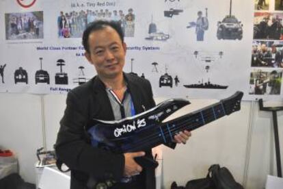 Sam Ong, director de la consultora singapurense TRD, posa en la Feria de Aviación de Singapur con un objeto con forma de guitarra que contiene un inhibidor de frecuencia, una técnica llamada "jamming" que perturba la señal de radio emisora del dron e interrumpe su vuelo.