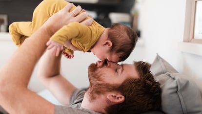 Un papá cogiendo a su hijo y dándole un beso.