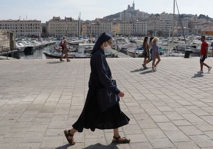 Una monja camina con mascarilla por el viejo puerto de Marsella