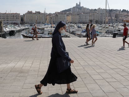 Una monja camina con mascarilla por el viejo puerto de Marsella