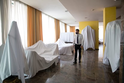 Un trabajador, junto a los muebles ocultos bajo sábanas de la recepción del hotel Amaragua, en Torremolinos.