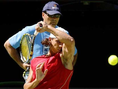 Rafa Nadal golpea con decisión la bola ante la atenta mirada de su tío Toni.