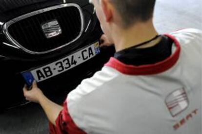 Un experto coloca una placa nueva en un coche. EFE/Archivo