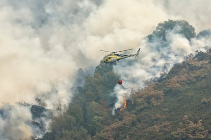 Un helicóptero descarga agua sobre las llamas de la ladera junto al Teixadal de Casaio, en Ourense.