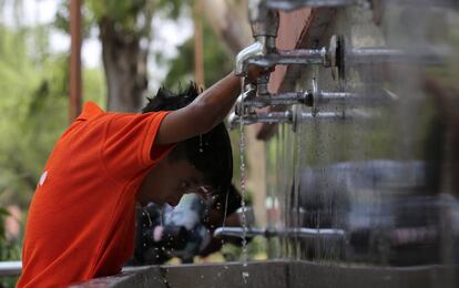Un niño se refresca bajo una fuente pública una calurosa mañana en Nueva Delhi, India.
