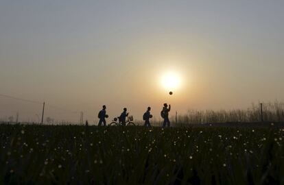 Unos estudiantes juegan con sus pelotas de ftbol mientras caminan por campos de cultivo para llegar a la escuela en Sunji (China).