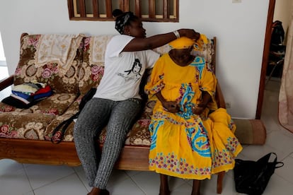 Khadjou Sambe ajusta el turbante a su abuela, Madicke Mbengue, en la casa familiar de Ngor, Dakar, el 29 de julio de 2020.