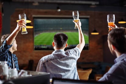 Aficionados viendo un partido de fútbol en un bar.