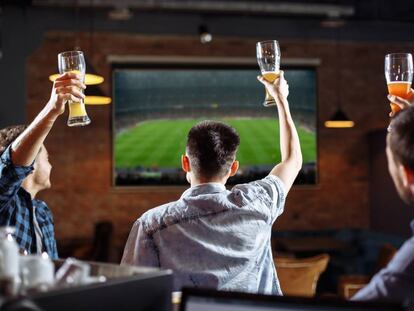 Aficionados viendo un partido de fútbol en un bar.