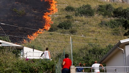 Residents look at flames burning in Capaci, near Palermo, in Sicily, southern Italy, Wednesday, July 26, 2023. 